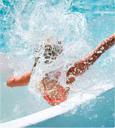 Persona saltando al agua con entusiasmo en la piscina.